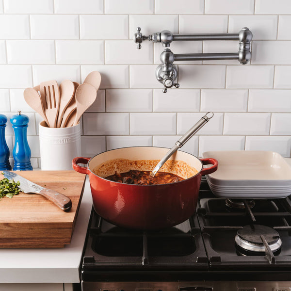 Cuisine::pro® LE CONNOISSEUR™ 6.6 Qt. Round French Oven on stove with cooking ingredients.